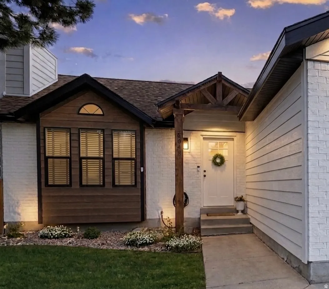 View of exterior entry featuring a yard and brick siding