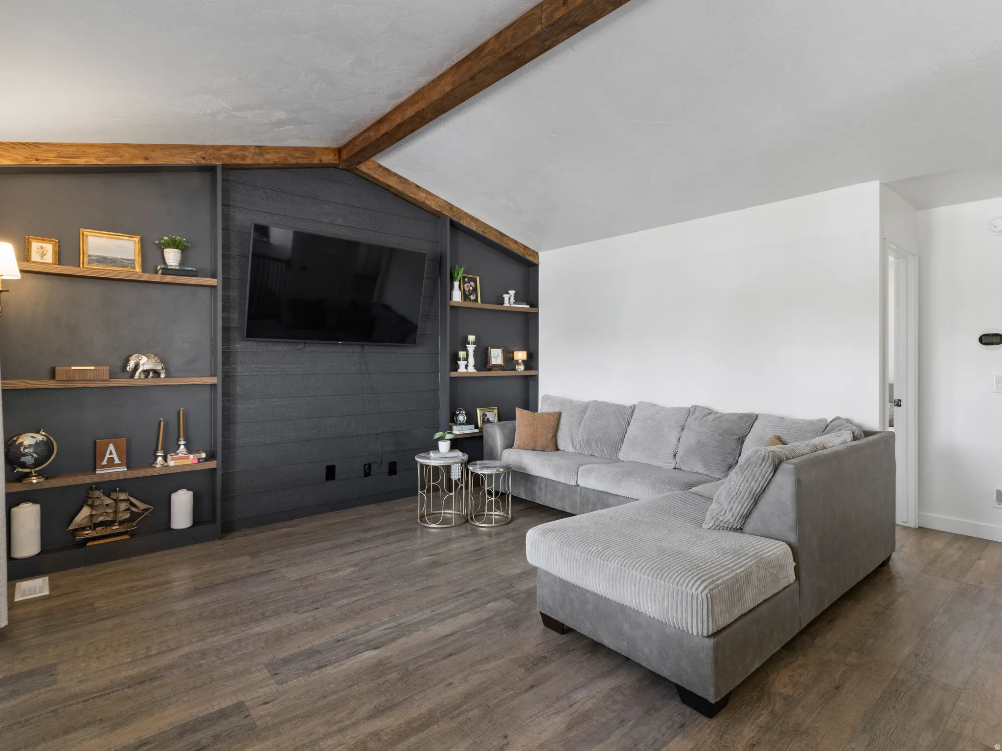 Living area with built in features, dark wood-style flooring, and beam ceiling