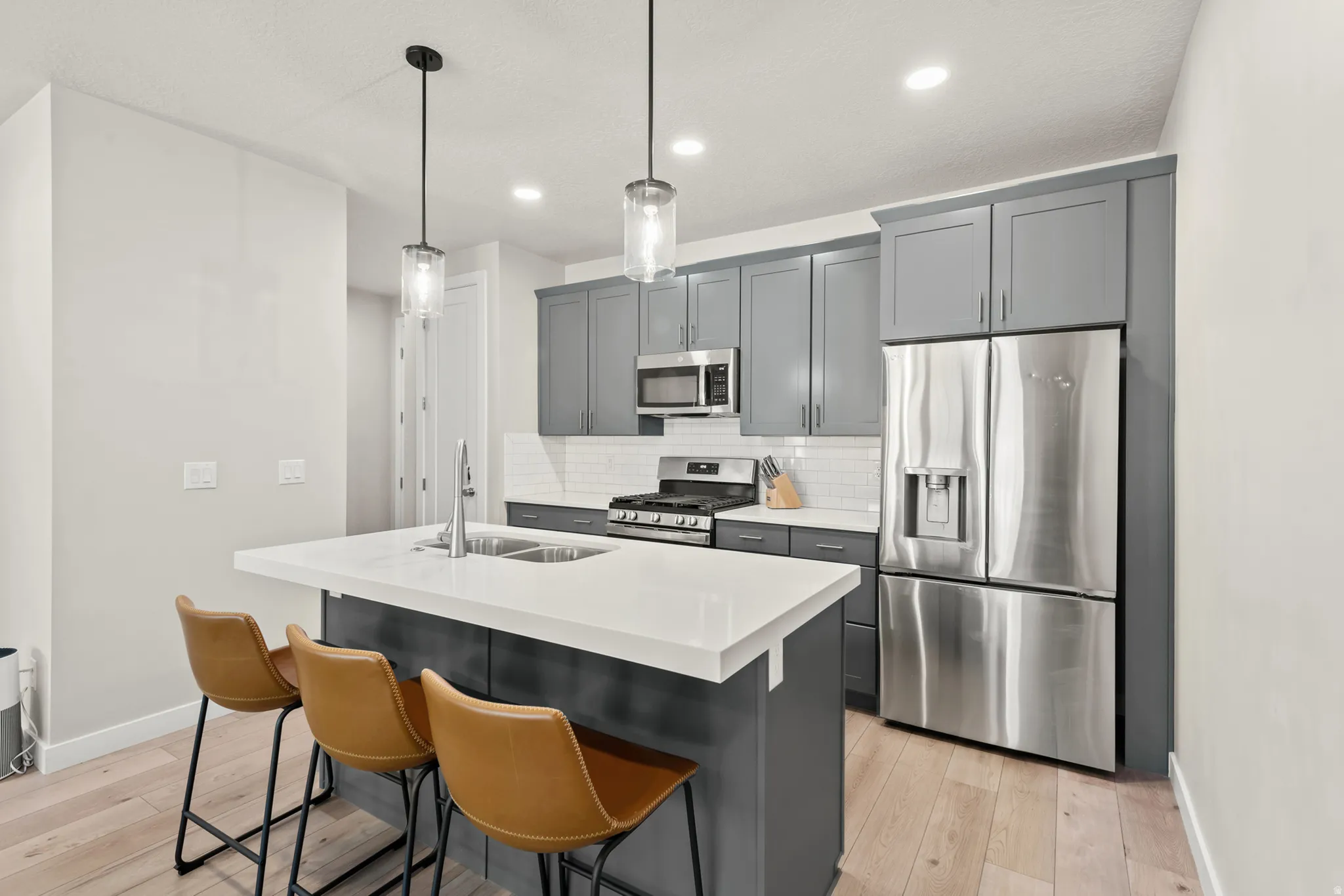 Modern kitchen featuring light wood-finish flooring and grey cabinetry