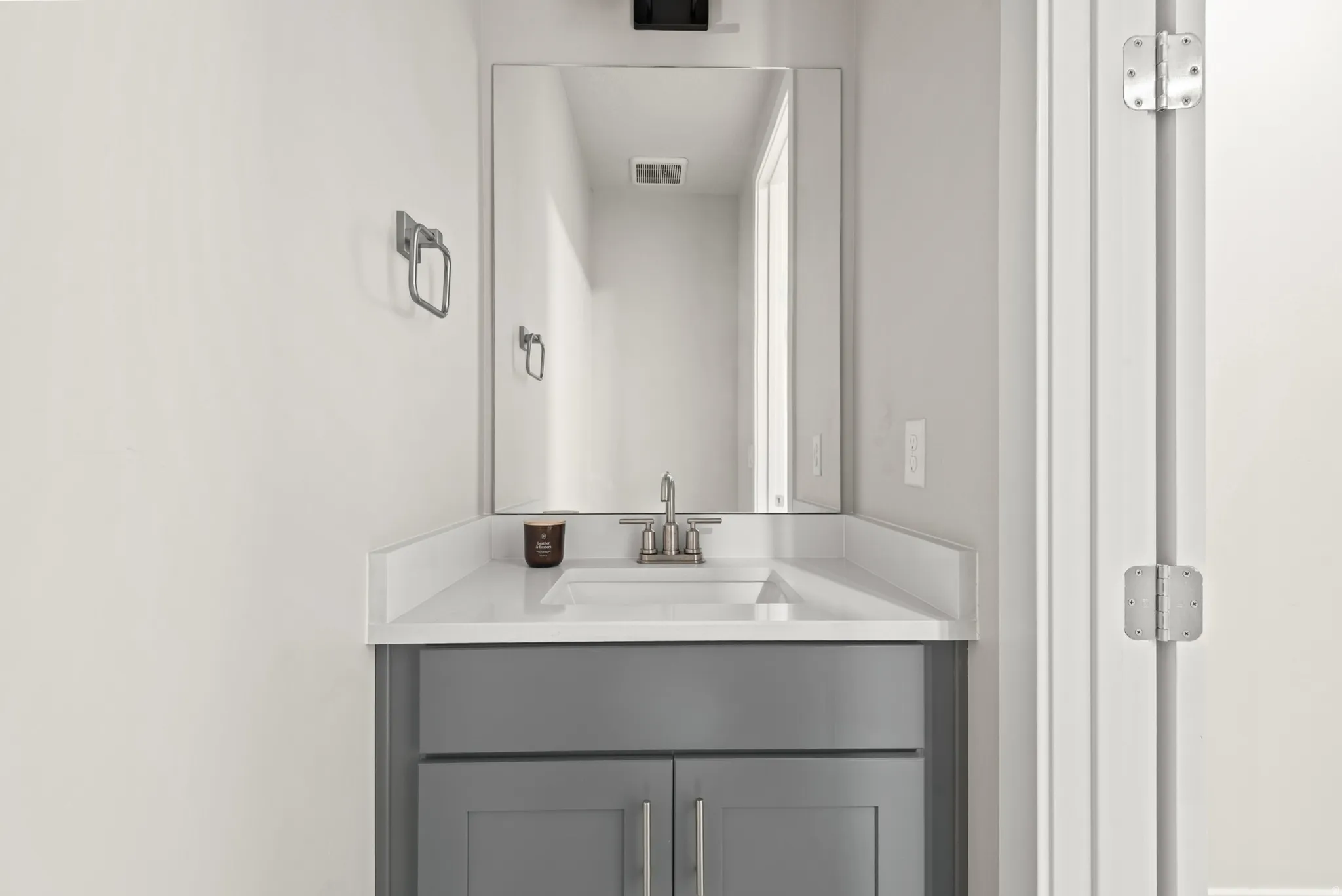 Contemporary vanity with gray cabinetry, white countertop, and integrated sink