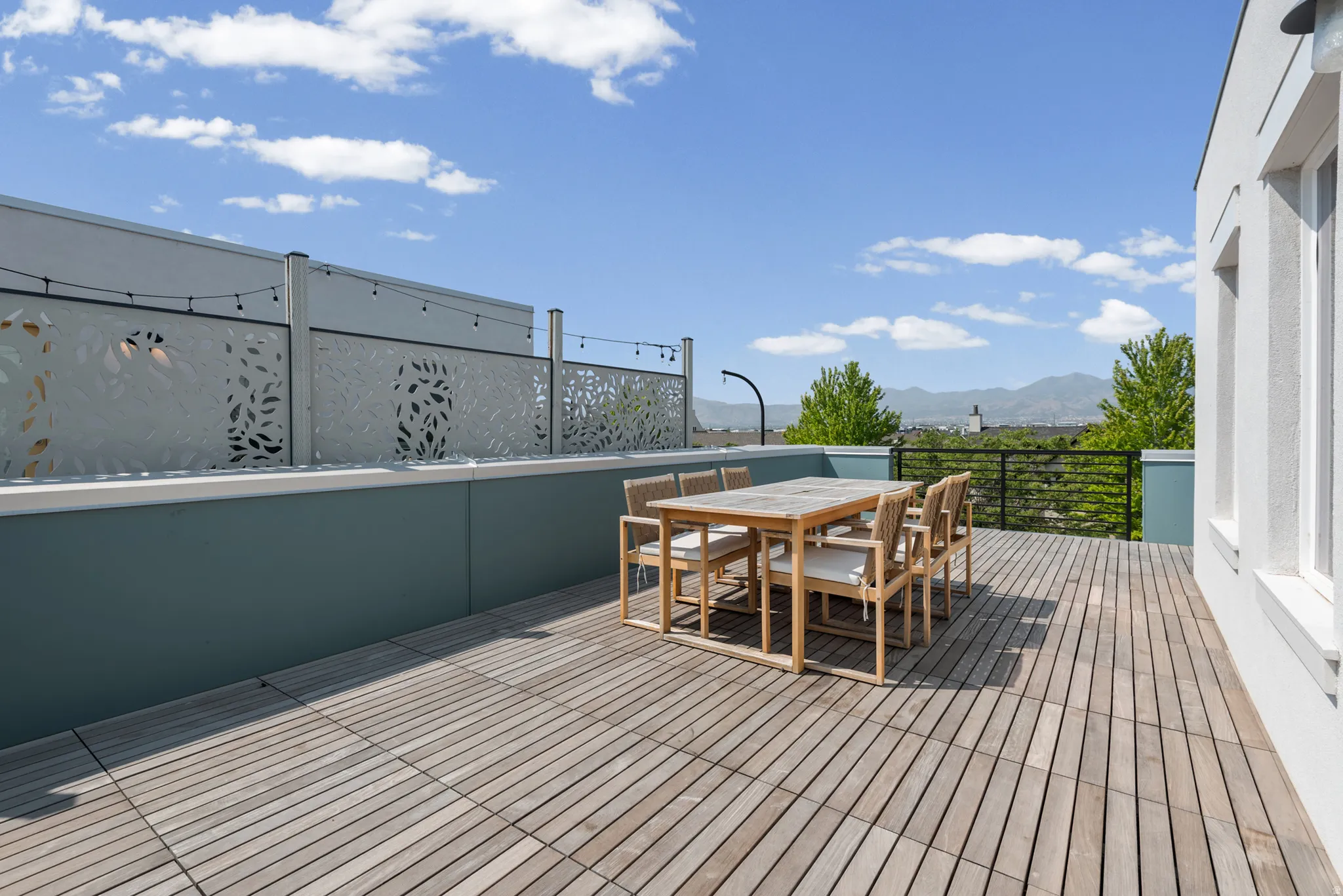 Rooftop patio featuring wood-finish flooring, decorative privacy screens, and mountain scenery