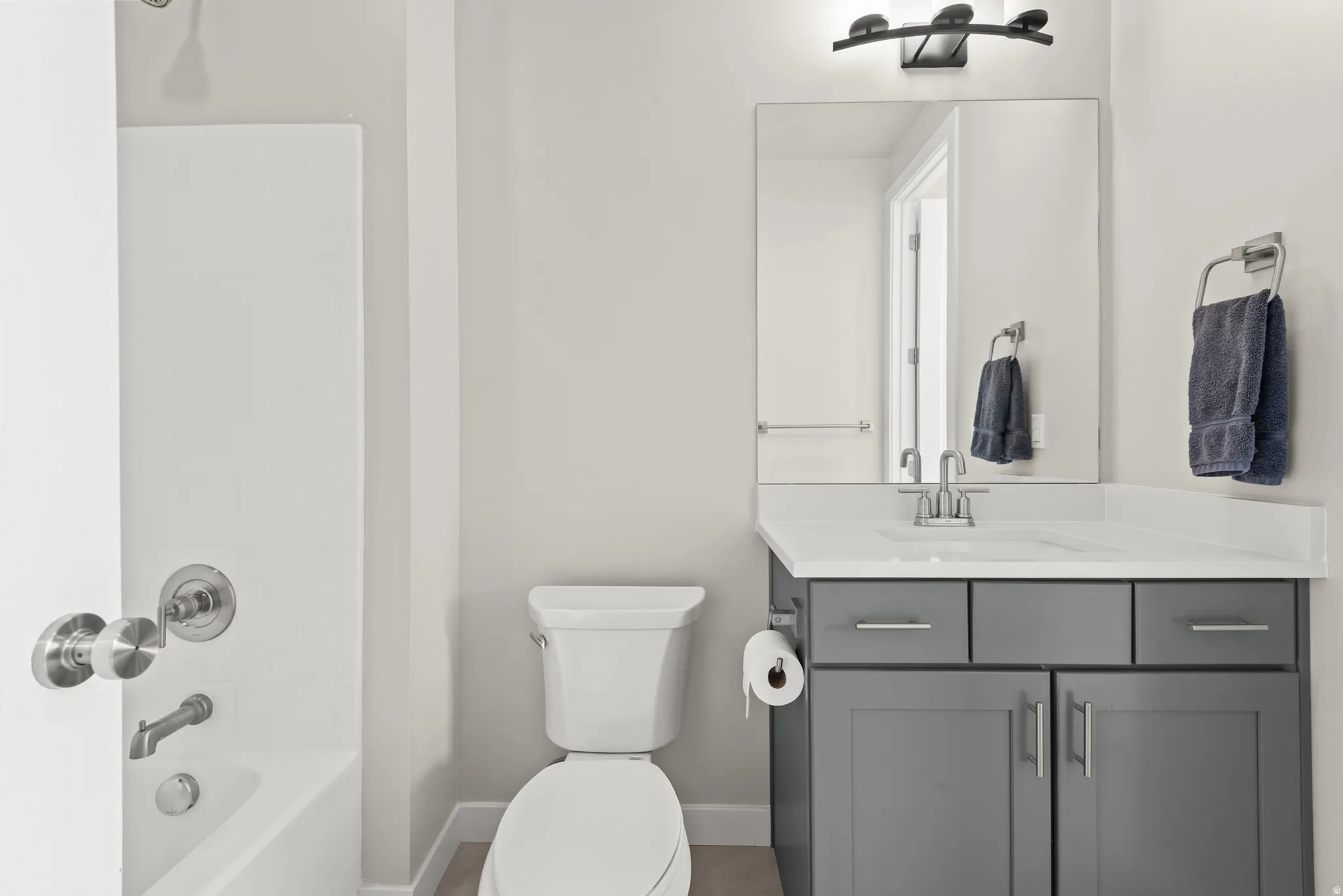 Bathroom with gray vanity, white countertop, integrated sink, and brushed nickel fixtures