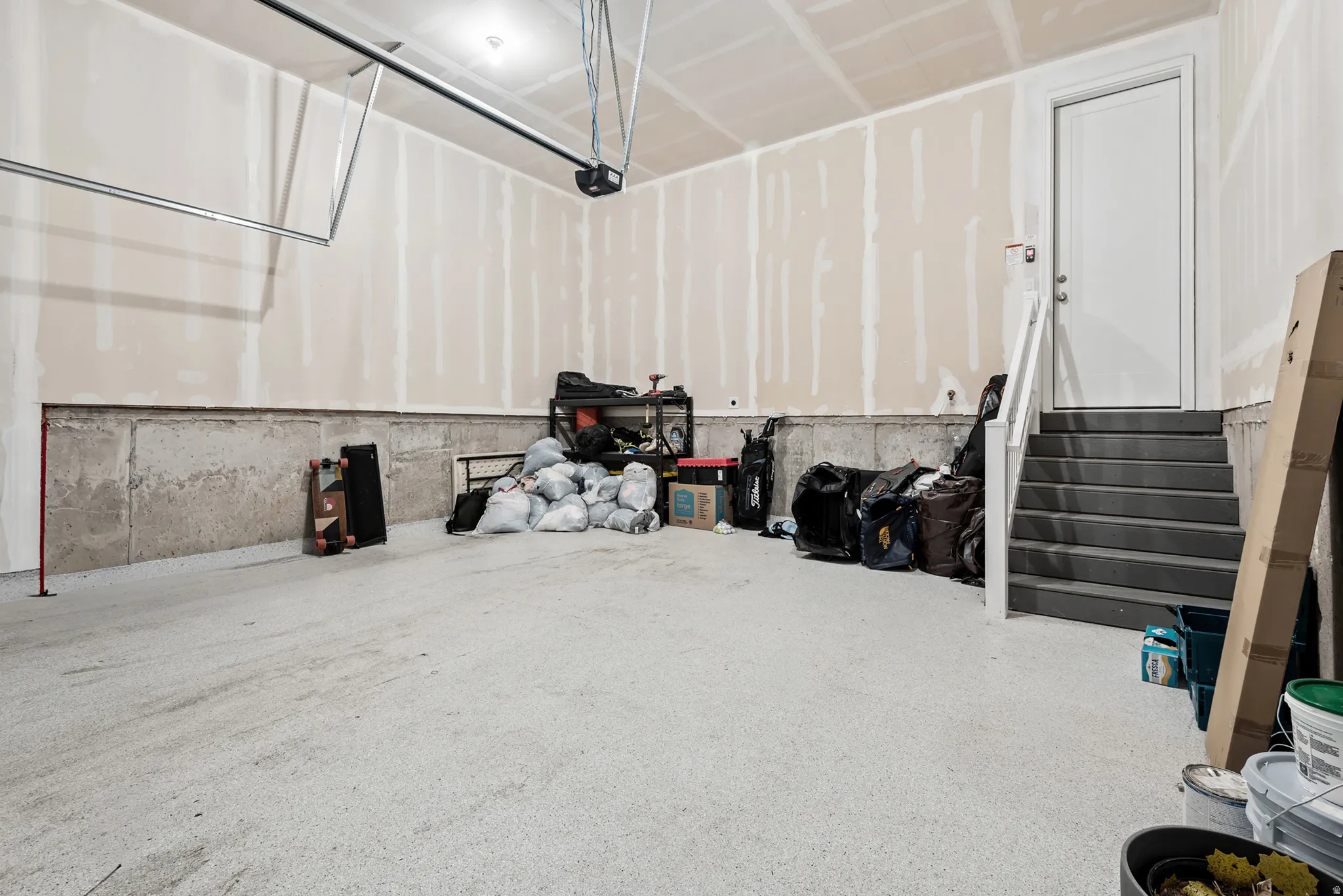 Spacious garage featuring a durable concrete floor, an overhead garage door opener mechanism, and unfinished drywall walls