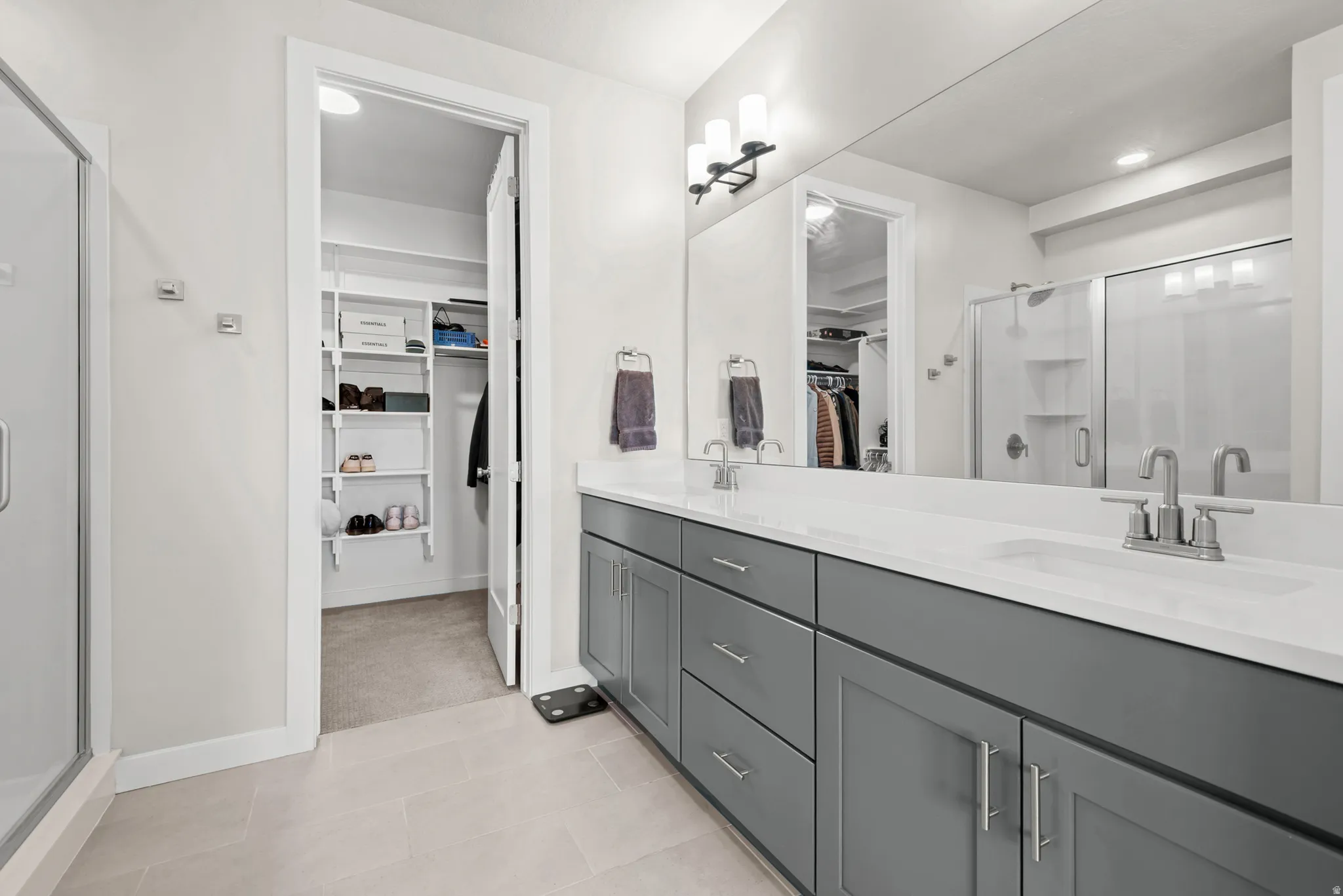 Contemporary bathroom featuring a double vanity with gray cabinetry, white countertops, and dual undermount sinks