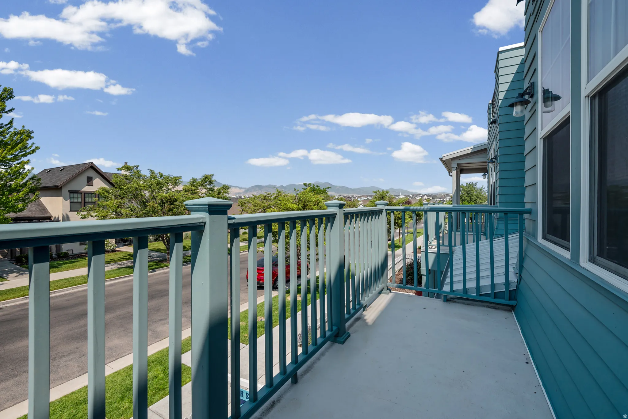 Private balcony featuring a teal railing, concrete flooring, and horizontal siding