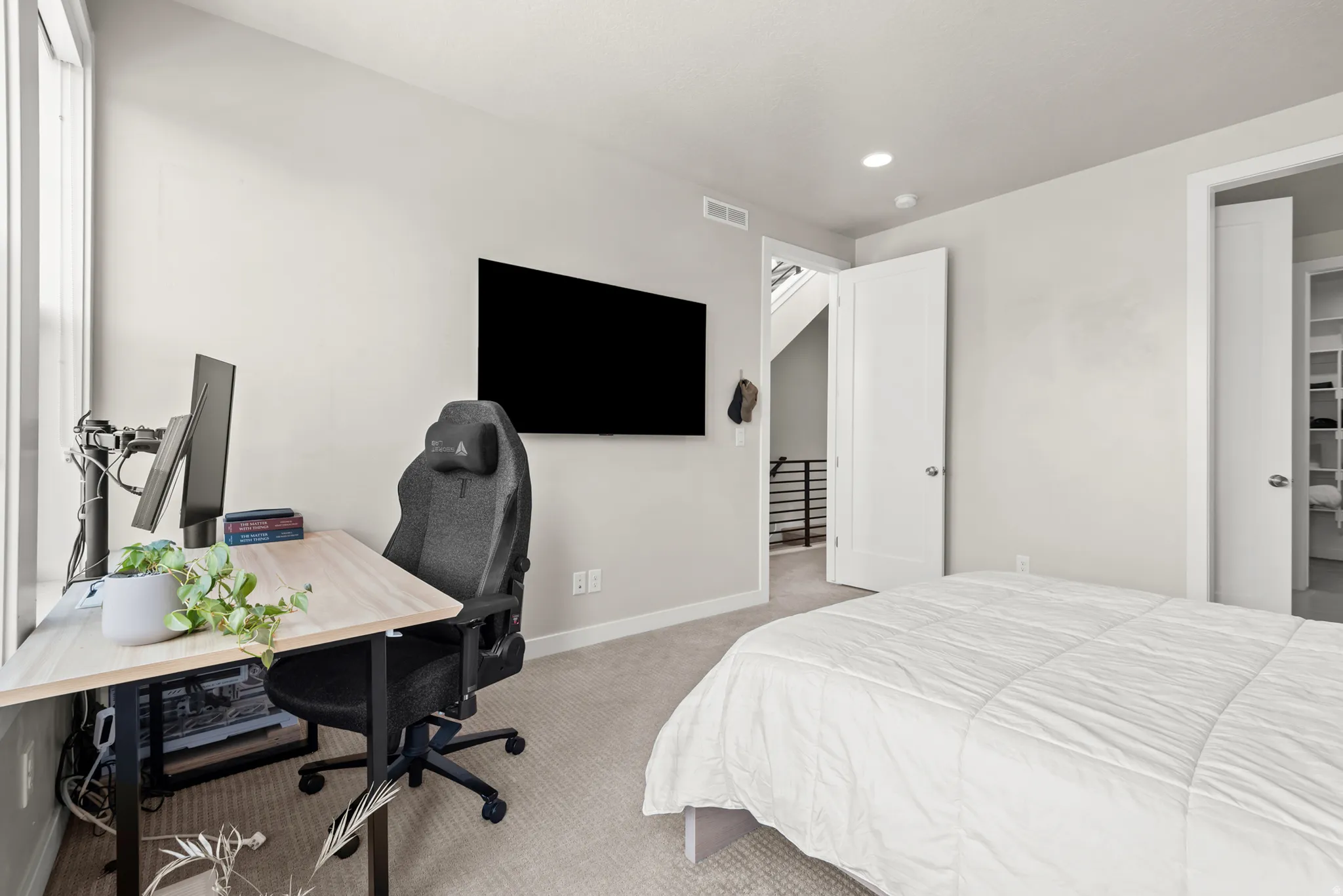 Carpeted room featuring a window with abundant natural light, recessed lighting, and a wall-mounted television