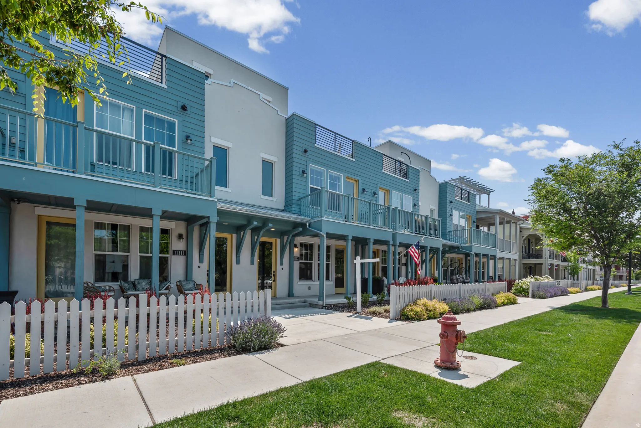 Contemporary townhome with a distinctive blue and white exterior, featuring a private balcony and a covered patio
