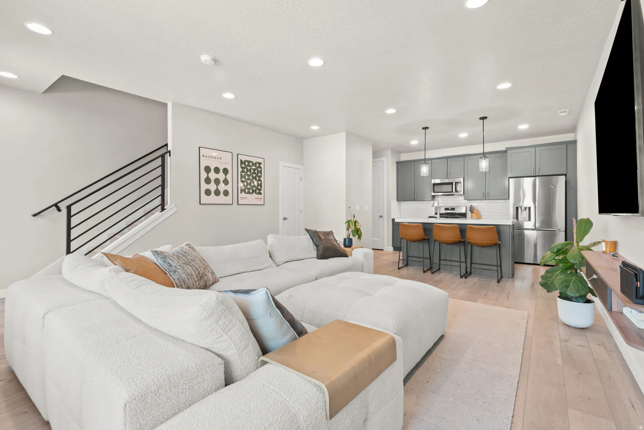 Open-concept living area featuring light wood-finish flooring, recessed lighting, and a modern kitchen
