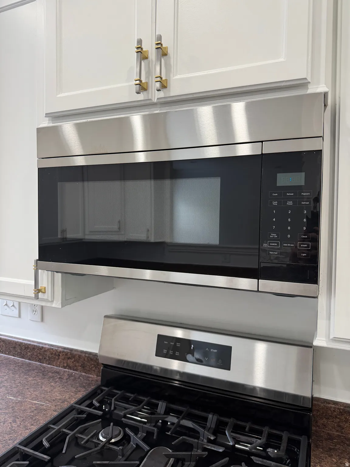 Kitchen view of stainless steel appliances and white cabinetry