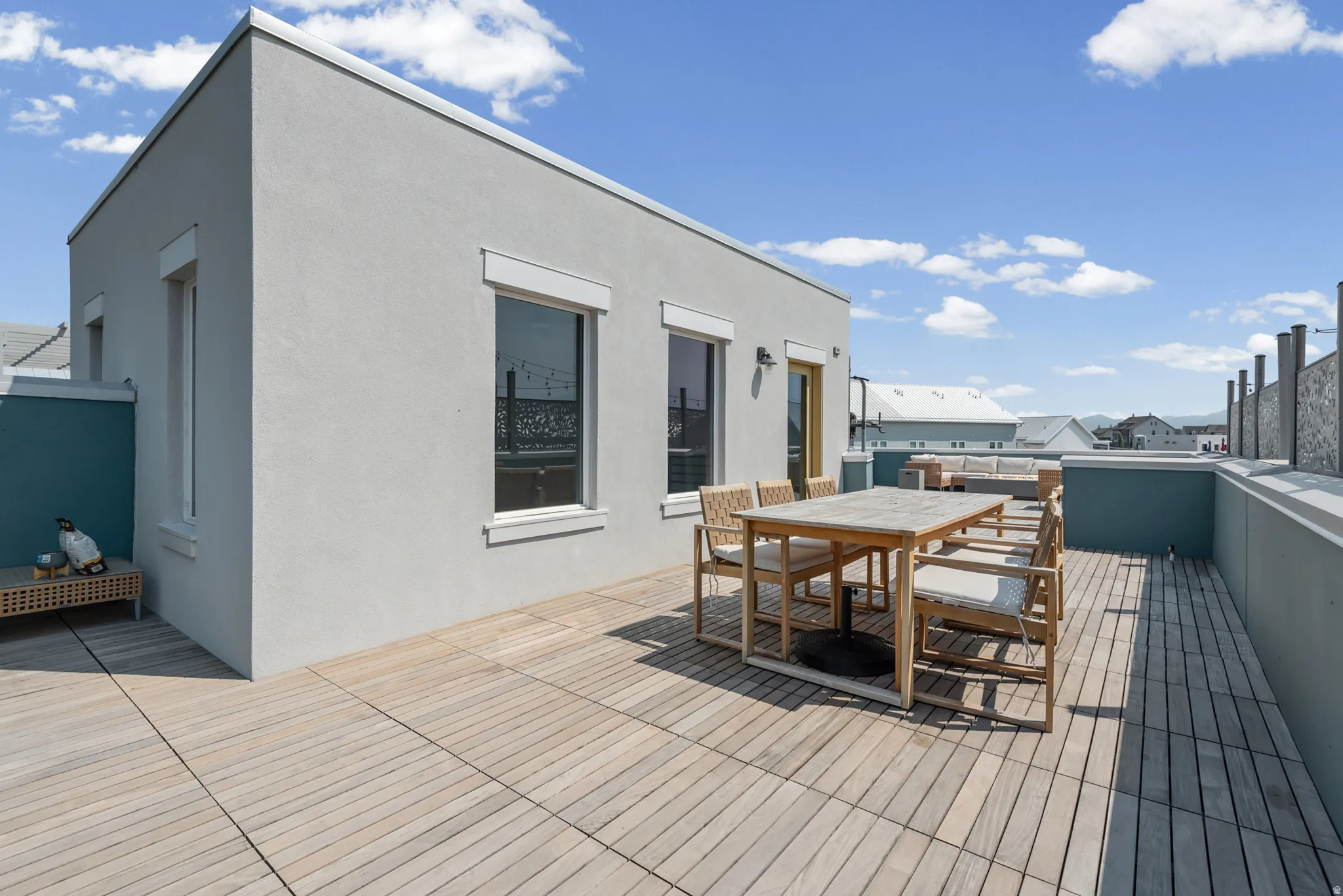 Expansive rooftop terrace featuring wood-finish decking, stucco exterior, and privacy walls