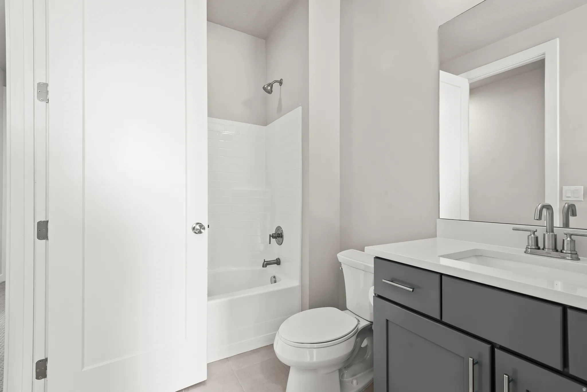 Bathroom featuring a dark gray vanity with chrome hardware, an integrated sink, and a large mirror