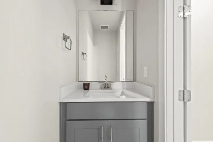 Contemporary vanity with gray cabinetry, white countertop, and integrated sink