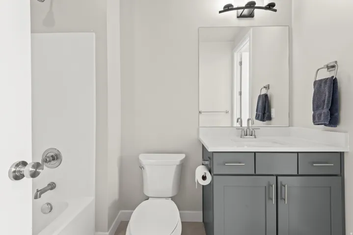 Bathroom with gray vanity, white countertop, integrated sink, and brushed nickel fixtures