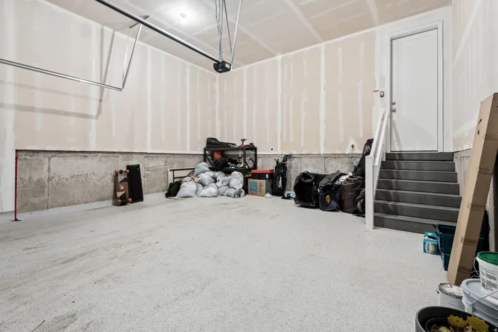 Spacious garage featuring a durable concrete floor, an overhead garage door opener mechanism, and unfinished drywall walls