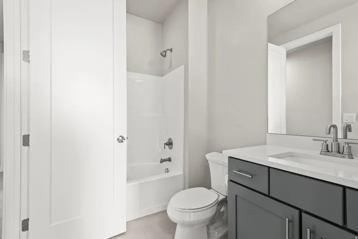 Bathroom featuring a dark gray vanity with chrome hardware, an integrated sink, and a large mirror