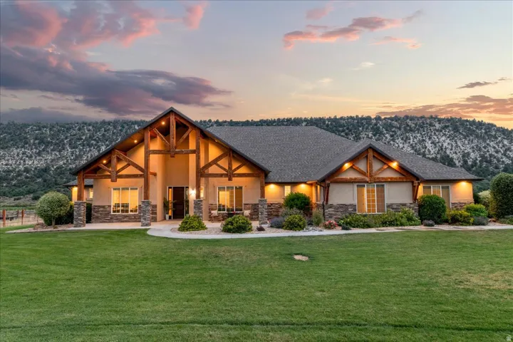 Craftsman-style home with stone siding, stucco siding, a front yard, and a porch