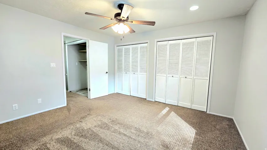 Unfurnished bedroom with multiple closets, carpet, and a ceiling fan