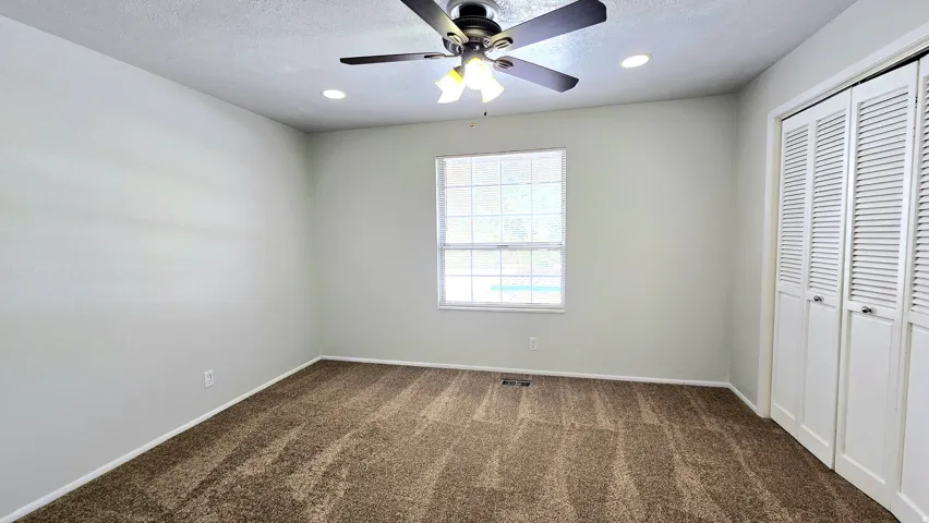 Unfurnished bedroom featuring a closet, dark colored carpet, a ceiling fan, and recessed lighting