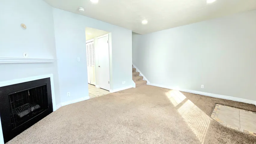 Unfurnished living room with light colored carpet, a fireplace, and recessed lighting