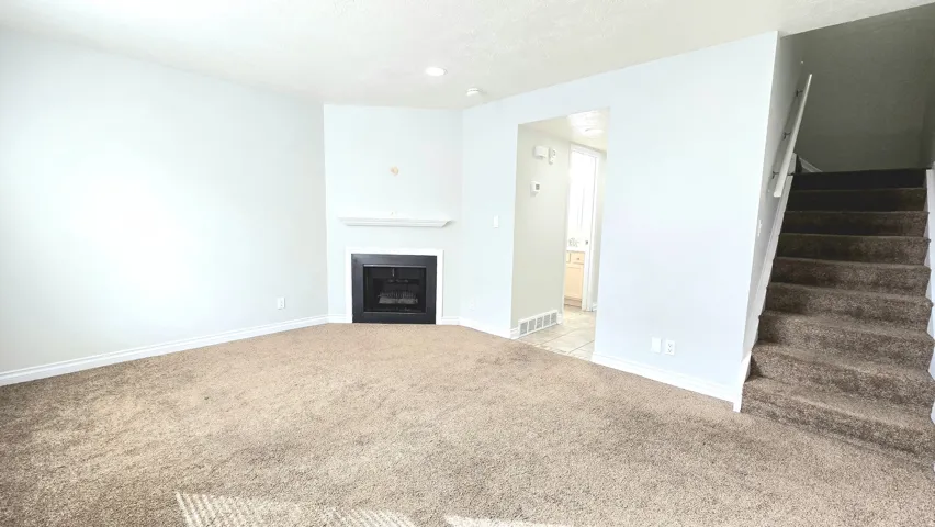 Unfurnished living room with light carpet and a fireplace