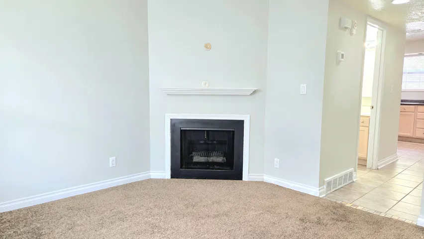 Unfurnished living room with light carpet, a fireplace, and light tile patterned floors