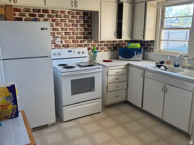 Kitchen with light flooring, white appliances, and white cabinetry