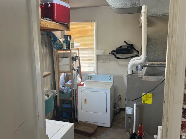 Laundry area with washer / clothes dryer, unfinished concrete floors, and heating unit