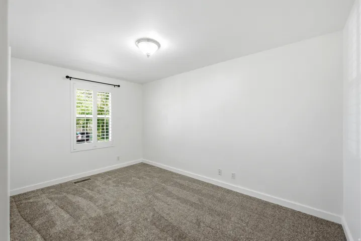 Empty room with baseboards and dark colored carpet