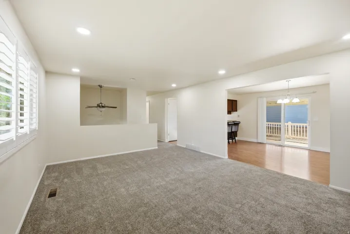 Spare room with healthy amount of natural light, light colored carpet, and suspended lighting