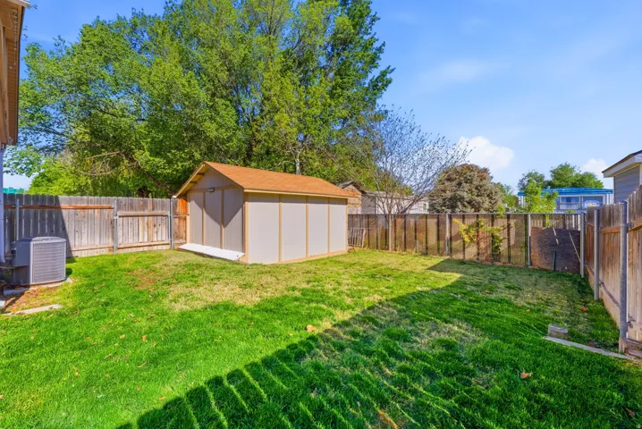 Fenced backyard featuring a storage shed
