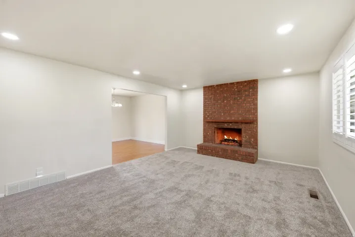 Unfurnished living room with light carpet, a fireplace, and recessed lighting