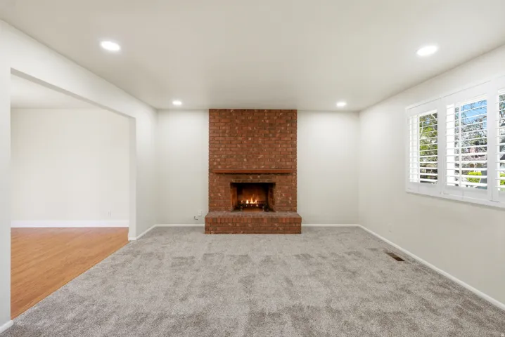 Unfurnished living room featuring light colored carpet, a fireplace, and recessed lighting