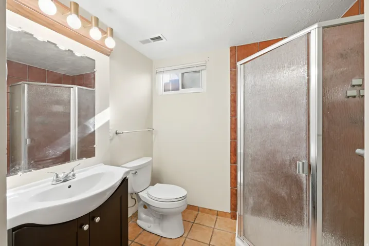 Full bath featuring vanity, a shower stall, light tile patterned floors, and a textured ceiling