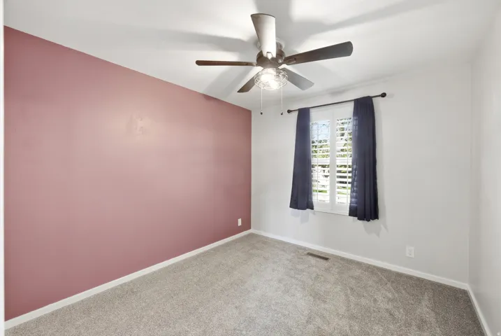 Empty room featuring a ceiling fan and carpet floors