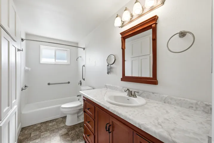 Bathroom featuring vanity, bathtub / shower combination, and stone finish flooring