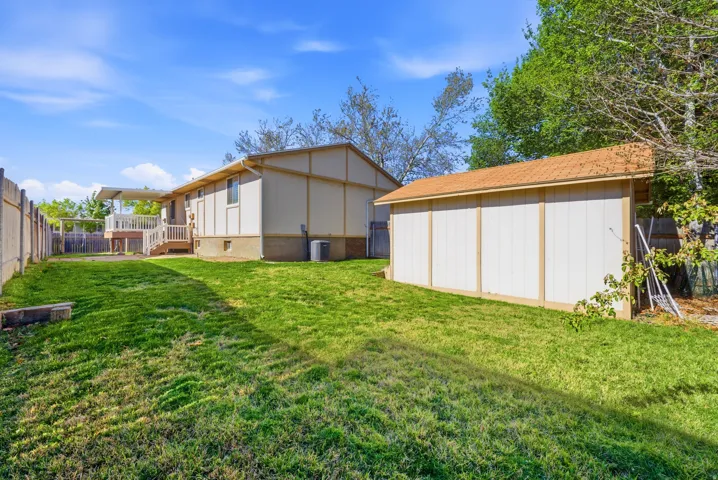 Rear view of house featuring a wooden deck and a shed