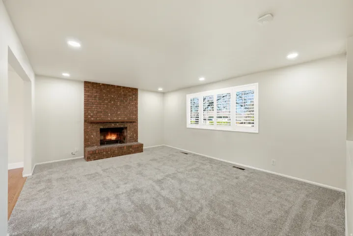 Unfurnished living room featuring light carpet, a fireplace, and recessed lighting