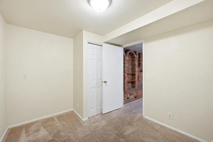 Unfurnished bedroom with light carpet, a closet, and a textured ceiling