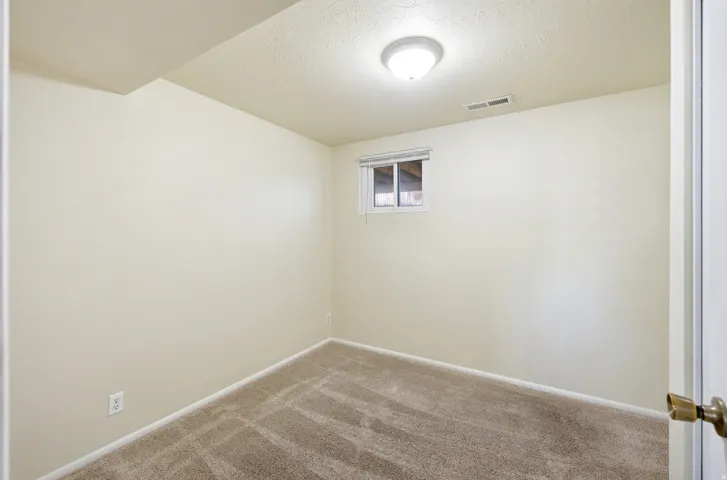Empty room with a textured ceiling and carpet floors