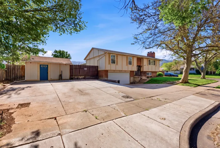 View of front of home with an attached garage, concrete driveway, a chimney, and brick siding