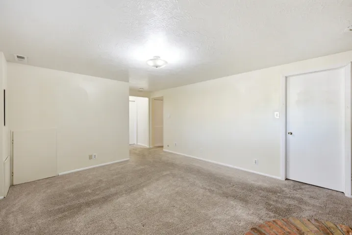 Empty room with a textured ceiling and carpet floors