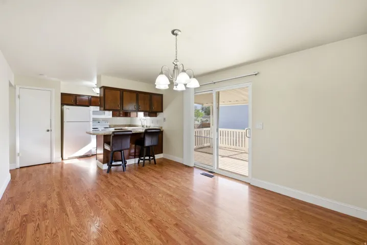 Kitchen with a chandelier, a peninsula, white appliances, dark wood finish cabinetry, and light countertops