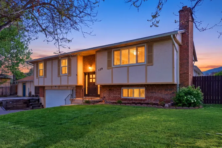 Split foyer home with a chimney, brick siding, an attached garage, and stucco siding