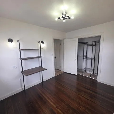 Unfurnished bedroom with dark wood finished floors and a closet