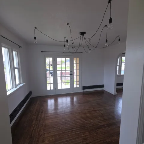 Unfurnished dining area featuring arched walkways, dark wood-type flooring, and suspended lighting