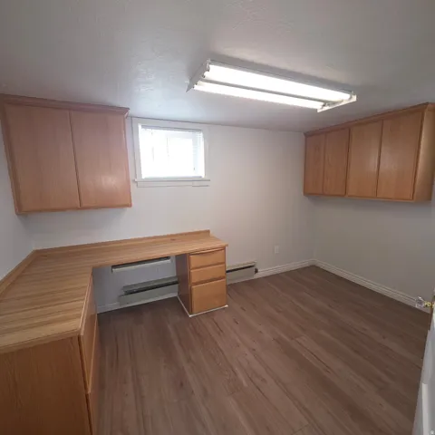 Unfurnished office featuring dark wood-style flooring, a textured ceiling, baseboard heating, and a baseboard heating unit
