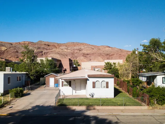 View of front of house with a mountain view, a fenced front yard, concrete driveway, and an outbuilding
