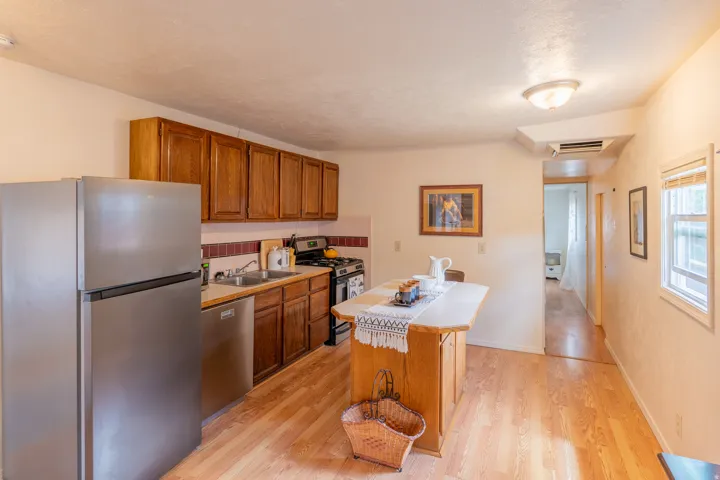 Kitchen featuring stainless steel appliances, light countertops, wood finish cabinets, light wood finished floors, and a kitchen island