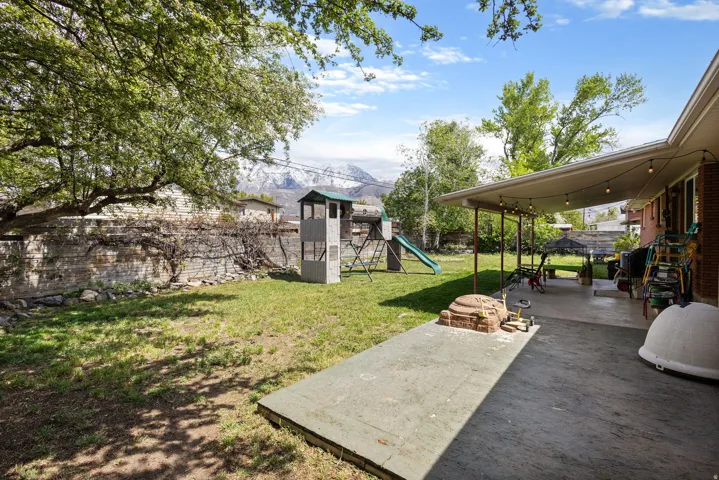 Fenced backyard featuring a playground, a patio area, and a mountain view