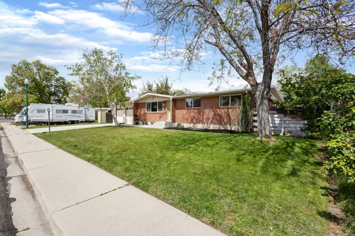 View of front of house with concrete driveway, an attached garage, a front yard, and brick siding